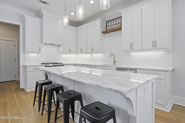 kitchen with open shelves, a breakfast bar area, white cabinets, and a sink