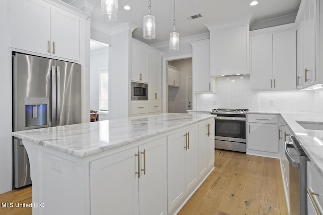 kitchen featuring ornamental molding, tasteful backsplash, a center island, stainless steel appliances, and white cabinets