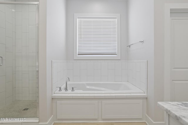 full bathroom featuring a stall shower, baseboards, and a garden tub