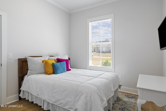 bedroom featuring wood finished floors, baseboards, and ornamental molding