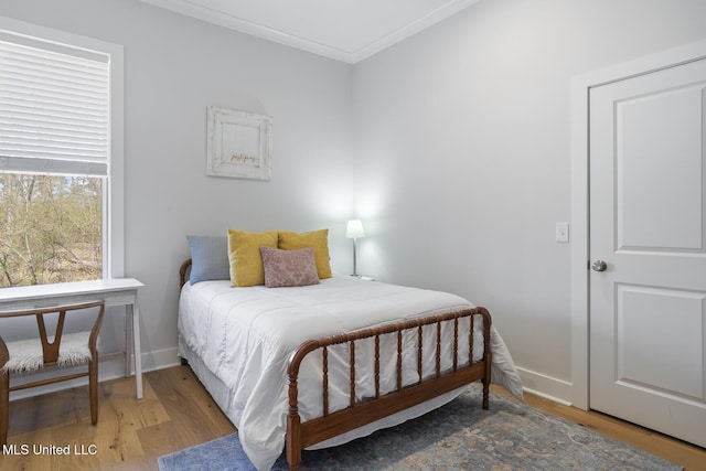 bedroom with ornamental molding, baseboards, and wood finished floors