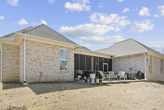 back of house with a patio area, brick siding, a sunroom, and a shingled roof