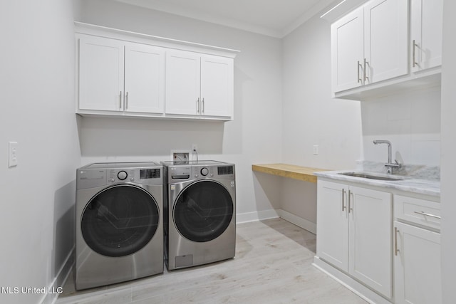 washroom with cabinet space, a sink, light wood-style floors, crown molding, and independent washer and dryer