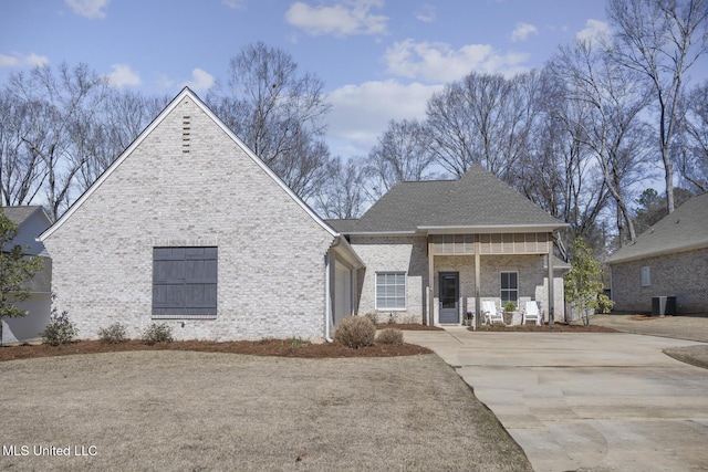 view of front facade with brick siding, central air condition unit, driveway, and roof with shingles