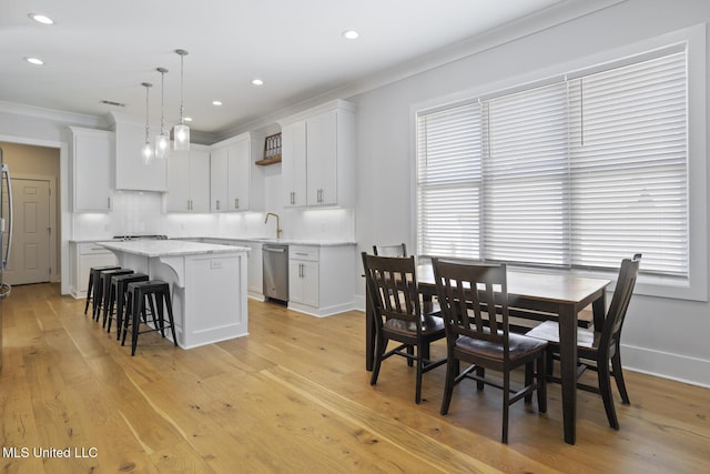 dining area featuring crown molding, light wood-type flooring, and baseboards