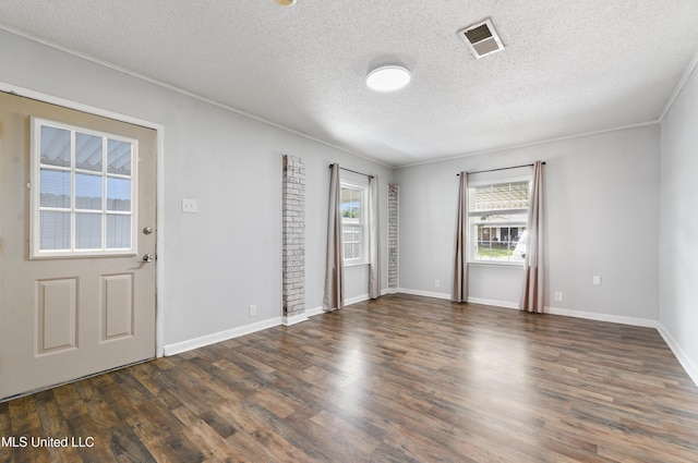 unfurnished room with a textured ceiling, dark hardwood / wood-style floors, and ornamental molding