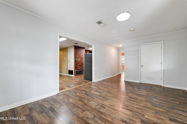 unfurnished room featuring a textured ceiling, dark hardwood / wood-style flooring, and brick wall