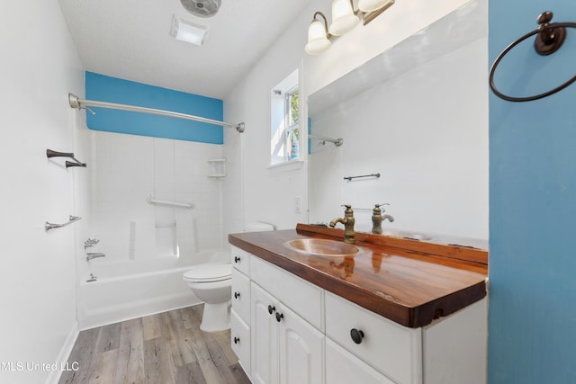 full bathroom with vanity, tiled shower / bath combo, toilet, a textured ceiling, and wood-type flooring