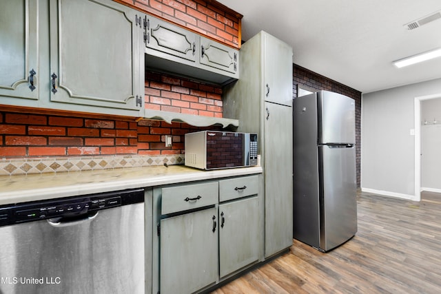 kitchen with tasteful backsplash, gray cabinets, light hardwood / wood-style flooring, and stainless steel appliances