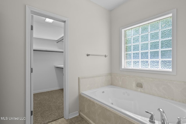 452 Pecan Cir, Brandon, MS 39042 - bathroom featuring a jetted tub, a walk in closet, and tile patterned flooring