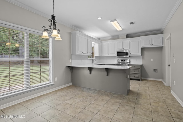 452 Pecan Cir, Brandon, MS 39042 - kitchen featuring stainless steel appliances, a peninsula, healthy amount of natural light, light tile patterned floors, and crown molding
