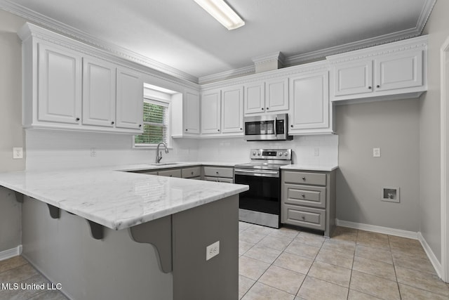 452 Pecan Cir, Brandon, MS 39042 - kitchen with appliances with stainless steel finishes, a peninsula, gray cabinets, tasteful backsplash, and ornamental molding