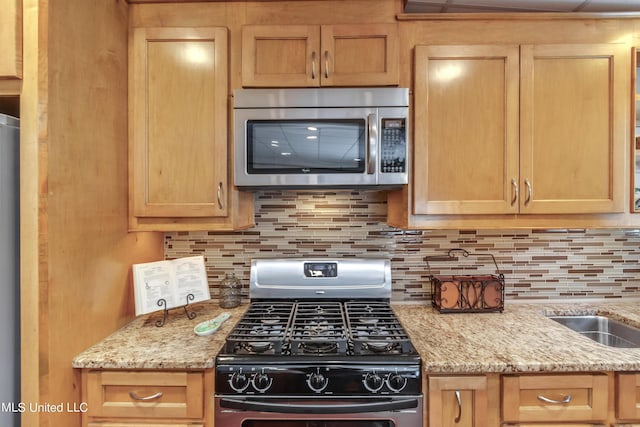904 Northwood Cir, Brandon, MS 39047 - kitchen featuring light brown cabinets, stainless steel microwave, light stone countertops, gas range, and decorative backsplash