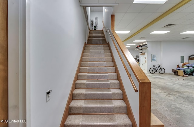 stairs with a drop ceiling and concrete flooring