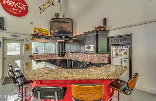 904 Northwood Cir, Brandon, MS 39047 - kitchen featuring built in microwave, backsplash, freestanding refrigerator, light stone countertops, and a kitchen bar