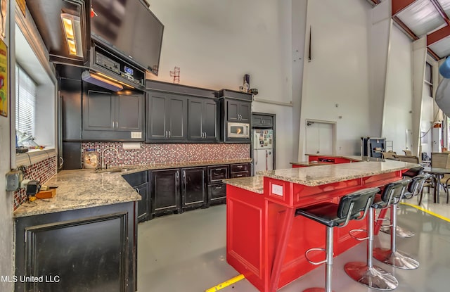 904 Northwood Cir, Brandon, MS 39047 - kitchen with a high ceiling, a sink, freestanding refrigerator, a center island, and decorative backsplash