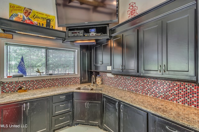 kitchen featuring light stone counters, tasteful backsplash, and sink