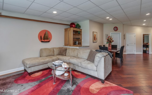 living room featuring a paneled ceiling and dark wood-type flooring