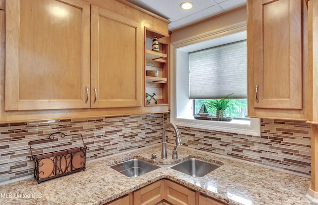 kitchen with sink, light stone countertops, and tasteful backsplash