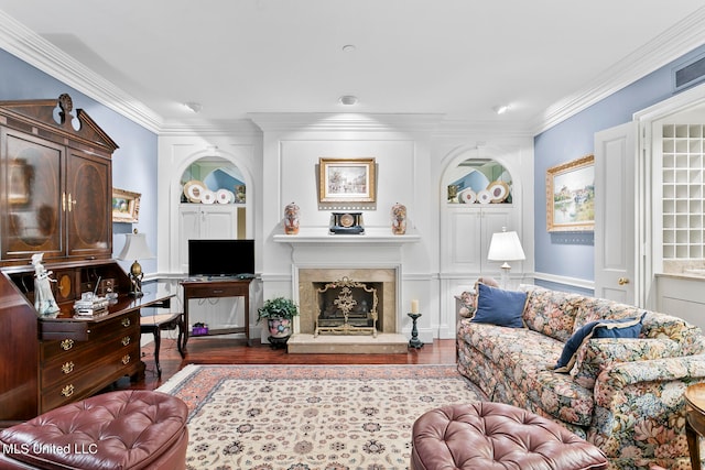 living room featuring a high end fireplace, crown molding, wood-type flooring, and built in features