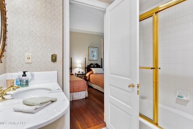 bathroom with bath / shower combo with glass door, ornamental molding, hardwood / wood-style flooring, and sink