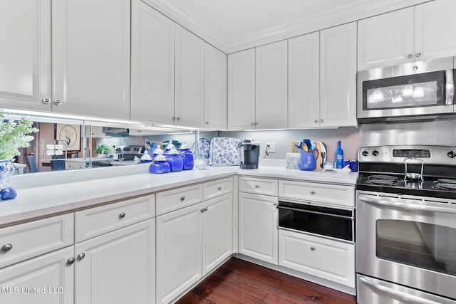 kitchen featuring crown molding, stainless steel appliances, dark hardwood / wood-style floors, and white cabinets