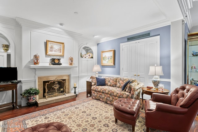 living room featuring built in features, ornamental molding, dark wood-type flooring, and a fireplace