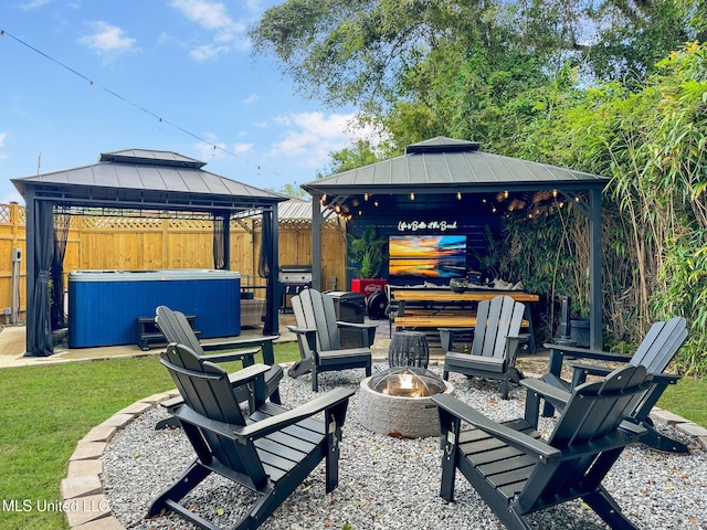 view of patio / terrace featuring a hot tub, grilling area, a gazebo, and an outdoor fire pit