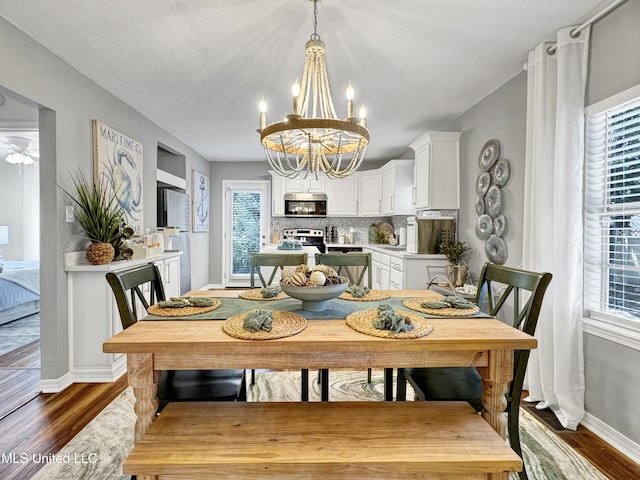 dining area with dark hardwood / wood-style floors, a textured ceiling, and an inviting chandelier