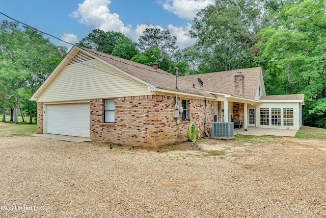 1597 Old Lake Rd, Brandon, MS 39042 - back of house featuring central air condition unit, driveway, an attached garage, a patio area, and roof with shingles
