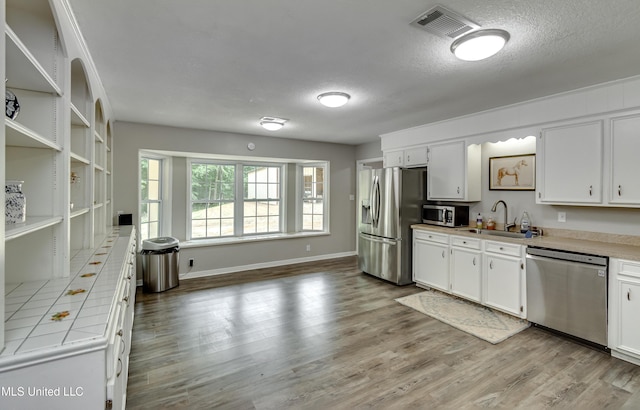 1597 Old Lake Rd, Brandon, MS 39042 - kitchen featuring stainless steel appliances, a sink, white cabinetry, light wood-style floors, and a textured ceiling