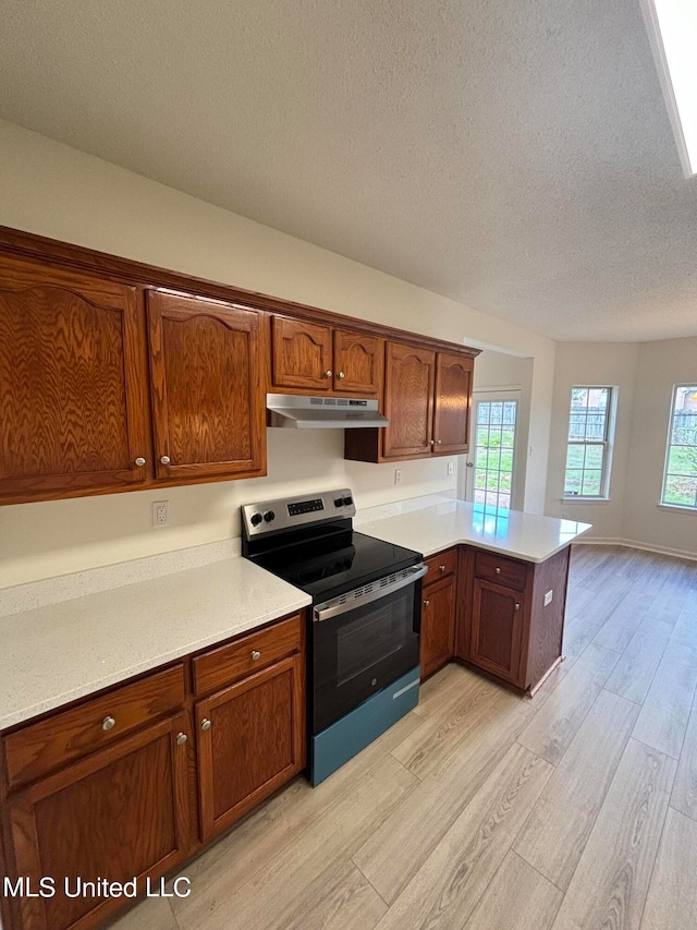 kitchen with stainless steel range with electric stovetop, kitchen peninsula, a textured ceiling, and light hardwood / wood-style floors