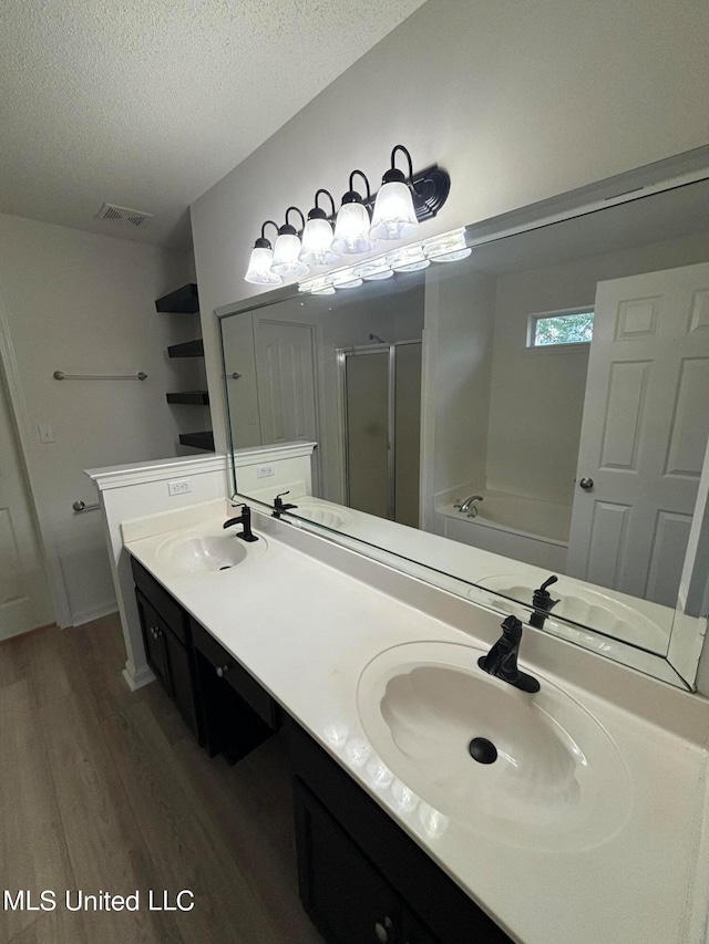 bathroom with vanity, hardwood / wood-style floors, shower with separate bathtub, and a textured ceiling