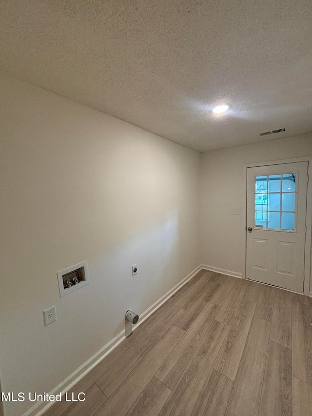 laundry area with electric dryer hookup, washer hookup, a textured ceiling, and light wood-type flooring