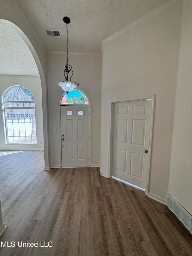 foyer entrance with a textured ceiling, ornamental molding, and hardwood / wood-style floors