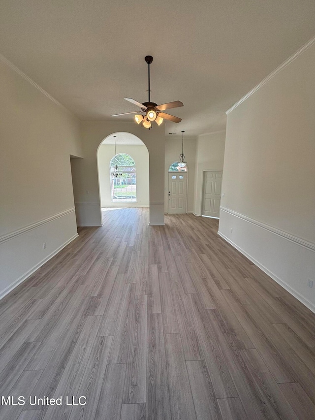 unfurnished living room featuring ceiling fan, crown molding, and light wood-type flooring