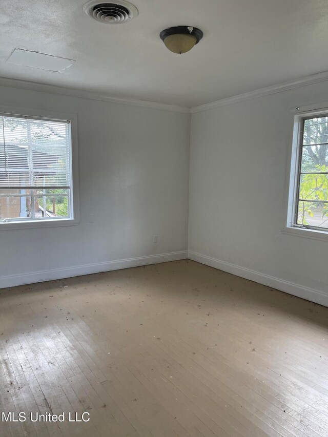 spare room featuring plenty of natural light, light hardwood / wood-style floors, and crown molding