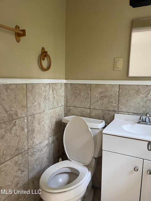 bathroom featuring vanity, toilet, and tile walls