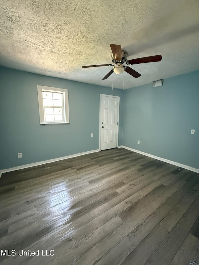 spare room featuring a textured ceiling, baseboards, dark wood-style flooring, and ceiling fan