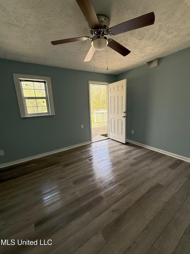 unfurnished room with plenty of natural light, dark wood-style floors, and ceiling fan