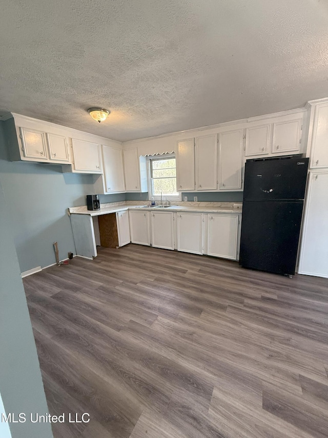 kitchen with dark wood-style floors, white cabinets, light countertops, and freestanding refrigerator