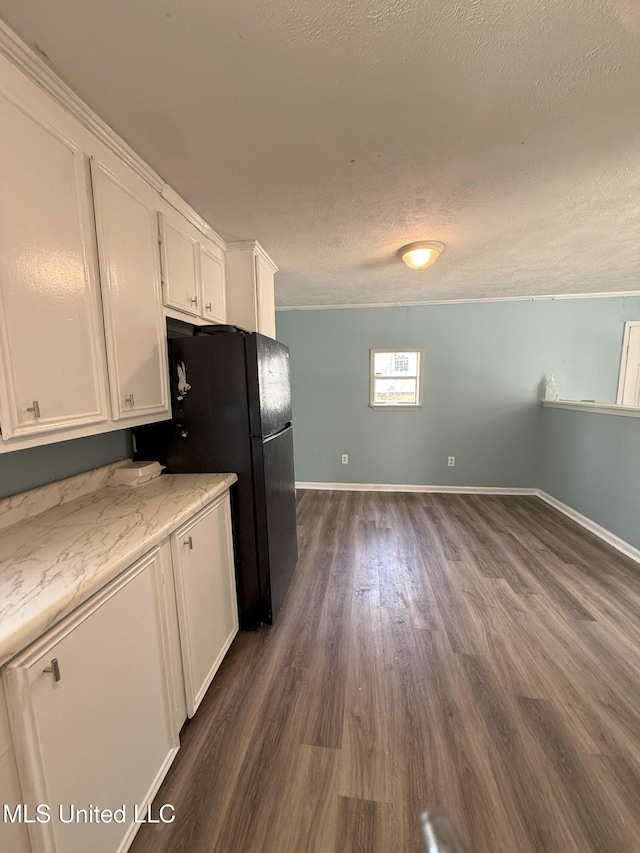 kitchen featuring baseboards, freestanding refrigerator, dark wood-type flooring, white cabinets, and a textured ceiling