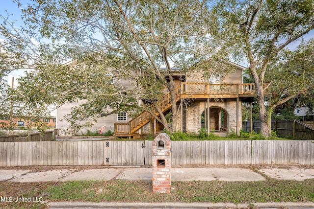 view of front of house featuring a fenced front yard, a gate, stairs, brick siding, and a deck