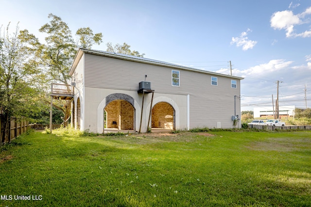 back of house featuring a lawn, fence, a deck, and central AC