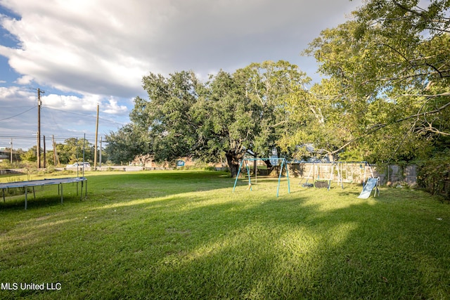 view of yard featuring fence, playground community, and a trampoline
