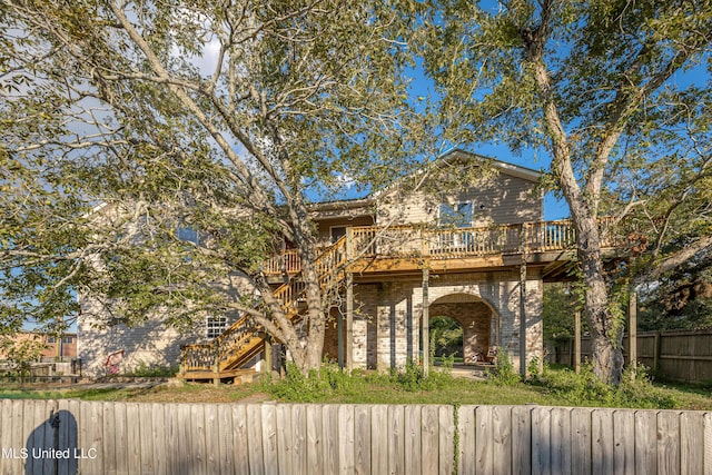 view of front facade with stairway, fence, a wooden deck, and brick siding