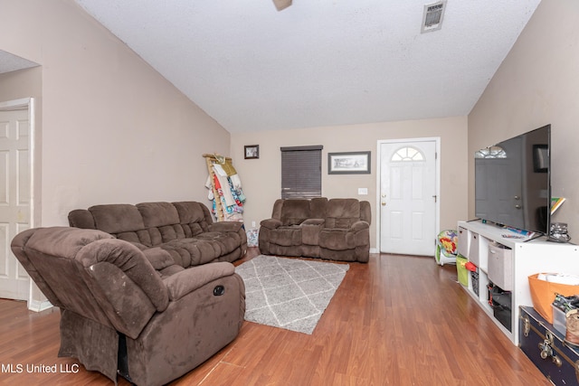 living room featuring a textured ceiling, hardwood / wood-style flooring, and vaulted ceiling