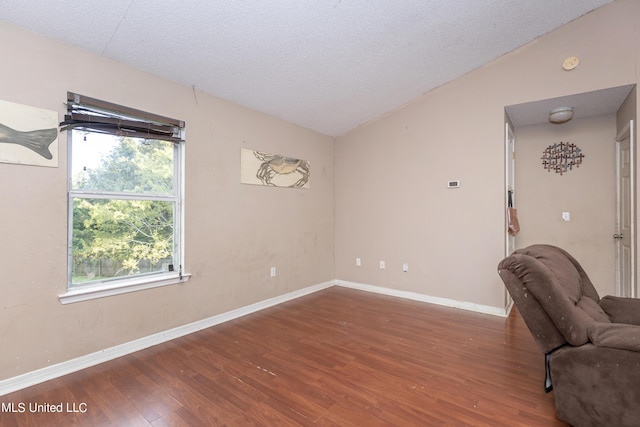 interior space with a textured ceiling, wood finished floors, and baseboards