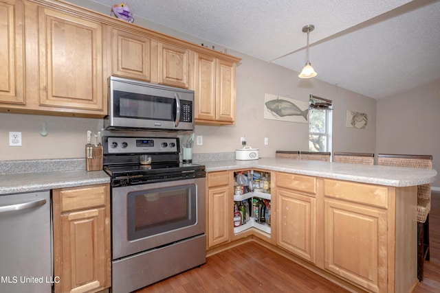 kitchen with appliances with stainless steel finishes, a textured ceiling, kitchen peninsula, hanging light fixtures, and light hardwood / wood-style flooring