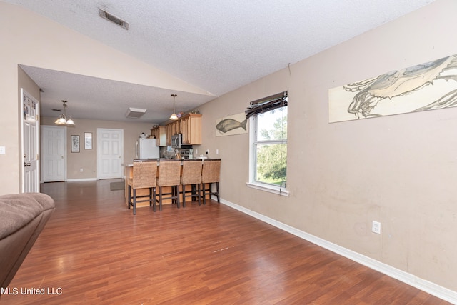 living room featuring a textured ceiling, dark wood-type flooring, and vaulted ceiling